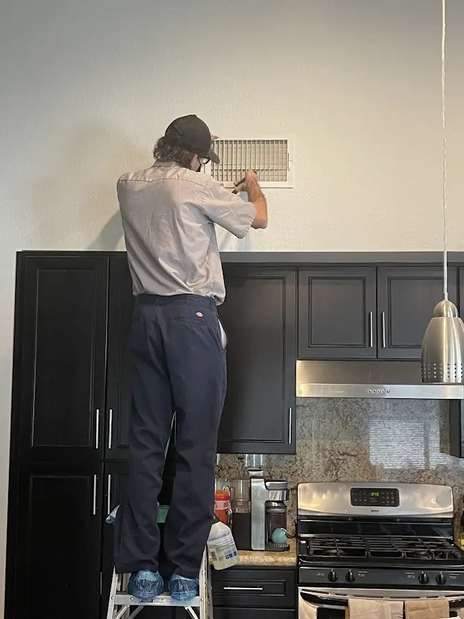 Technician inspecting an air vent during HVAC service in Savage